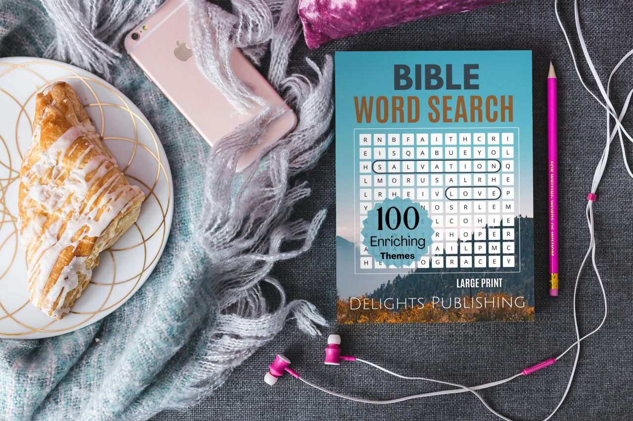 Contact 1 Top view of a Bible word search book next to a pencil, apple phone, and a Danish on a plate